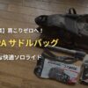 木の床に置かれたAPIDURA（アピデュラ）のサドルバッグと、収納する携帯ポンプや予備チューブなどの必須アイテム。ロードバイク初心者が身軽で快適なソロライド を楽しむための装備を解説するアイキャッチ画像。