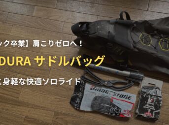 木の床に置かれたAPIDURA（アピデュラ）のサドルバッグと、収納する携帯ポンプや予備チューブなどの必須アイテム。ロードバイク初心者が身軽で快適なソロライド を楽しむための装備を解説するアイキャッチ画像。