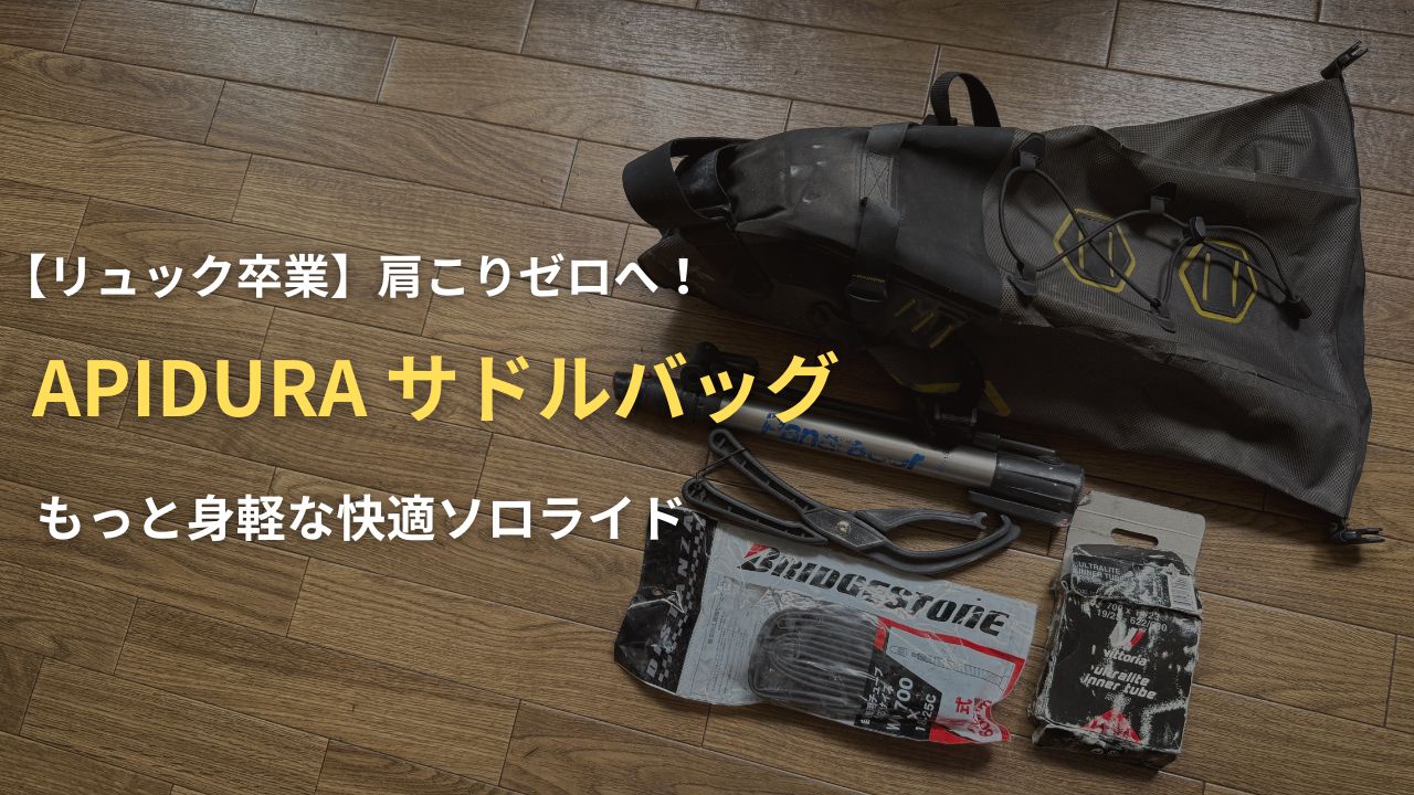 木の床に置かれたAPIDURA（アピデュラ）のサドルバッグと、収納する携帯ポンプや予備チューブなどの必須アイテム。ロードバイク初心者が身軽で快適なソロライド を楽しむための装備を解説するアイキャッチ画像。