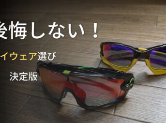 木の床に並べられた黒と黄色のオークリー製アイウェア。「後悔しない!アイウェア選び決定版」の文字が添えられ、ロードバイク初心者が紫外線や虫の衝突から目を守り、安全で快適なライドを楽しむための失敗しない選び方を分かりやすく解説する資料。