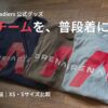 床に並べられたINEOS Grenadiersのロゴ入りパーカーとTシャツ2枚。「推しチームを、普段着に。」の文字がある。