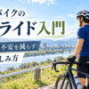 晴れ渡る青空の下、川沿いのサイクリングロードで遠くの景色を眺める男性サイクリスト。「ロードバイクのソロライド入門」の文字が添えられ、初心者が一人で走る不安を減らし、準備と楽しみ方を学ぶためのガイド用アイキャッチ。